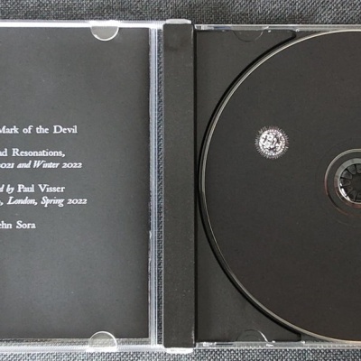 CD preto com texto branco na parte interior do estojo e padrão branco no disco.