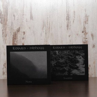Duas capas de discos de vinil Ildjarn - Nidhogg Norve e Svartråd sobre uma superfície escura junto a uma parede clara.