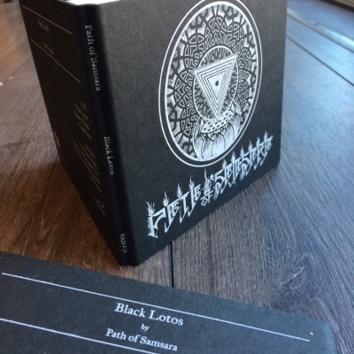 Caixa preta com padrão branco intricado e cartão com texto branco sobre madeira