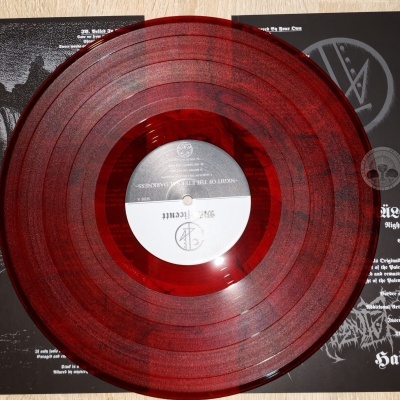 Disco de vinil vermelho transparente sobre capa aberta preta com texto branco