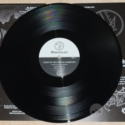 Disco de vinil preto com etiqueta central do álbum Night of the Eternal Darkness da banda Mäleficëntt sobre a capa de fundo preto com texto branco.