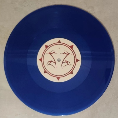 Disco de vinil azul com etiqueta central branca e padrão vermelho