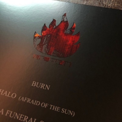 Capa preta fosca com desenho em relevo de chama vermelha e texto impresso em branco