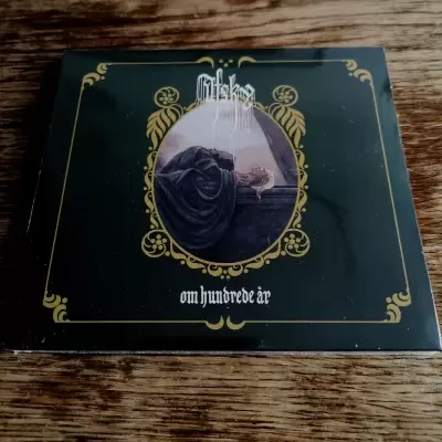 Caixa de álbum musical preta com moldura dourada e imagem de mulher deitada, texto MisterKa e om hundrede år.