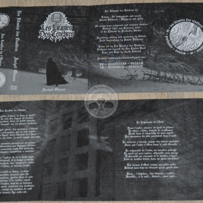 Capa de álbum musical negro com texto em francês e imagem de figura encapuzada e símbolos circulares