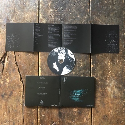 CD com capa e encarte preto com texto branco sobre mesa de madeira