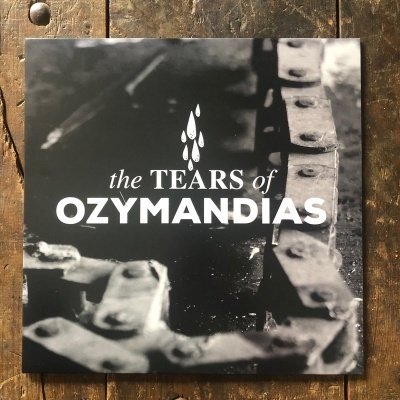 Capa de álbum preto e cinzento com texto 'the TEARS of OZYMANDIAS' e imagem de corrente metálica