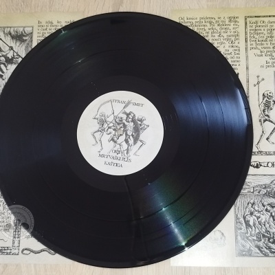 Disco de vinil preto com selo central branco e ilustrações em fundo com texto antigo