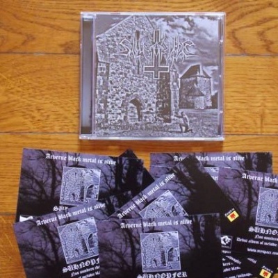 CD com capa cinzenta e flyers preto e branco sobre chão de madeira