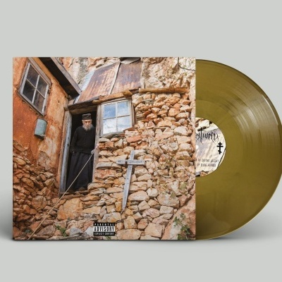Disco de vinil amarelo com capa mostrando homem e casa rústica de pedra e tijolo.