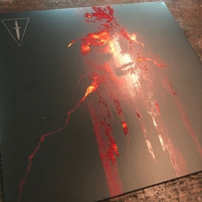 Capa de álbum preta com imagem abstrata vermelha brilhante e triângulo com adaga branca no canto superior esquerdo