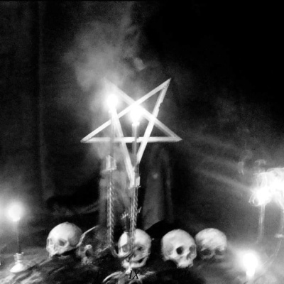 Estrela de paus com velas acesas e vários crânios dispostos em círculo rodeados por velas acesas