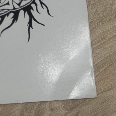 Ilustração preta de figura humana estilizada em papel branco sobre madeira clara