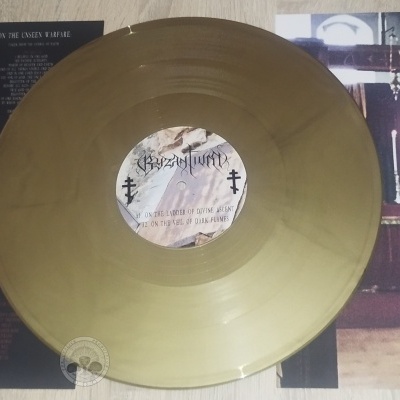 Disco de vinil dourado com encarte preto e poster com imagem religiosa