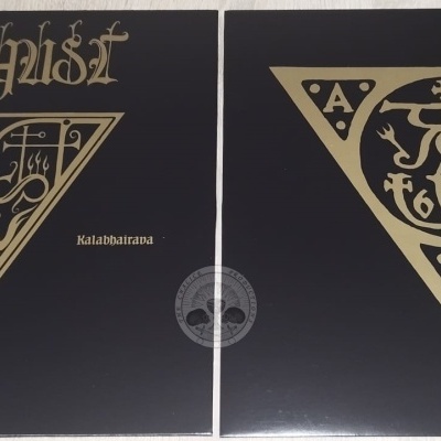 Capas de álbuns pretas e douradas com símbolos triangulares e texto estilizado sobre uma superfície clara