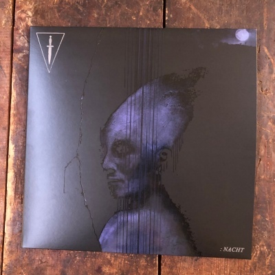 Capa de álbum preto com figura alienígena azul e símbolo triangular com adaga