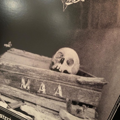 Caixão de madeira velho com letras M A A e crânio em cima