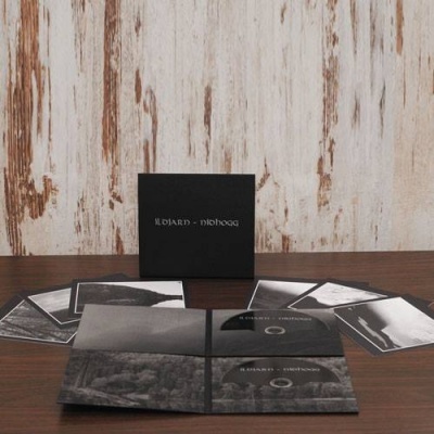 Conjunto de postais e um livro ou caixa preta numa mesa com fundo de madeira