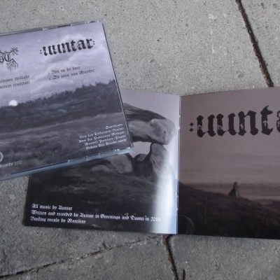 CD e encarte de álbum com arte obscura e texto gótico sobre chão de pedra