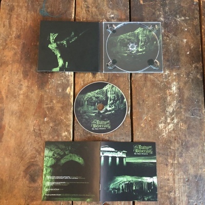 CD Phantom Reveracy No End of Death com arte de cavernas verde e preta, sobre mesa de madeira com livreto aberto.