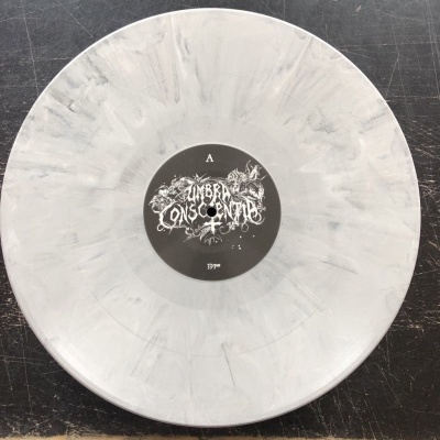 Vinil branco marmoreado com etiqueta preta e texto branco no centro sobre superfície escura