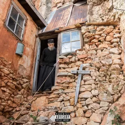 Parede rústica de pedra com cruz, janela de madeira e homem vestido de preto na porta