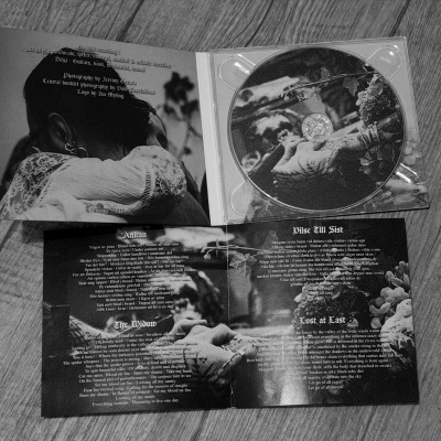 Estojo de CD com capa e livreto a preto e branco sobre madeira