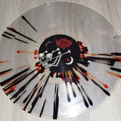 Disco de vinil transparente com manchas pretas e vermelhas e etiqueta central preta com esqueletos.