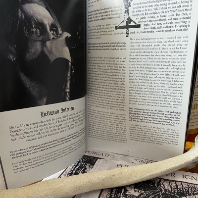 Livro aberto com texto em inglês e objeto alongado claro sobre superfície com outras publicações