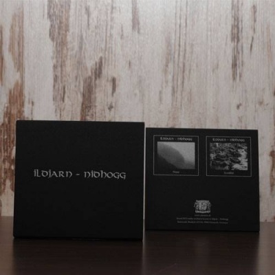 Caixa preta com texto 'ILDJARN - NITHOGG' e imagens na parte de trás sobre superfície escura e fundo de madeira clara