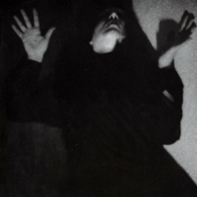 Pessoa com roupa preta e mãos levantadas em fotografia a preto e branco