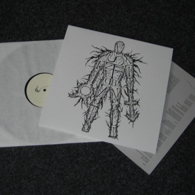 Vinil branco com capa ilustrada a preto e branco sobre carpete cinza