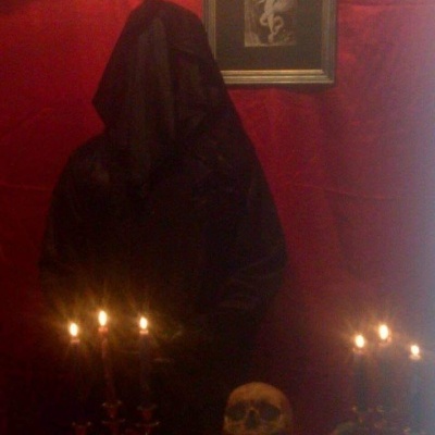 Figura encapuzada com capa preta, crânio, velas e ossos sobre superfície vermelha