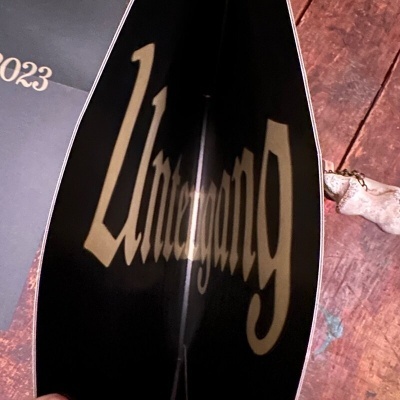 Livro aberto com capa preta e texto dourado, sobre uma superfície de madeira