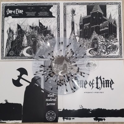 Vinil transparente com manchas pretas sobre capa de álbum em papel com arte a preto e branco e texto One of Time