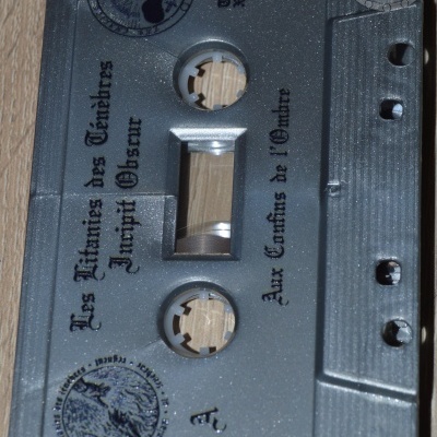 Cassete de áudio cinzenta com texto e símbolos pretos estilizados