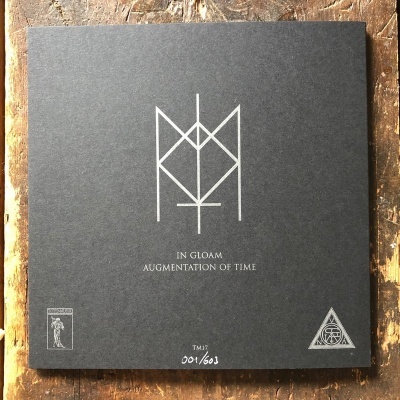 Capa preta quadrada com símbolos e texto branco sobre madeira