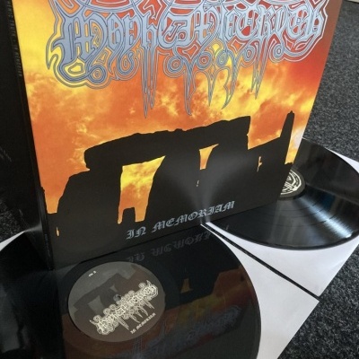 Vinil preto com capa em tons quentes e texto IN MEMORIAM