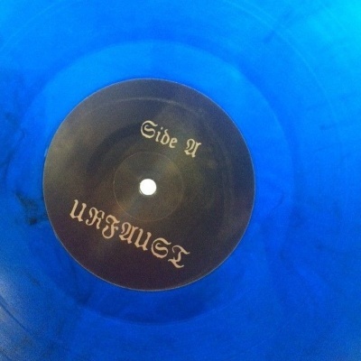 Disco de vinil azul translúcido com etiqueta preta e texto dourado no centro
