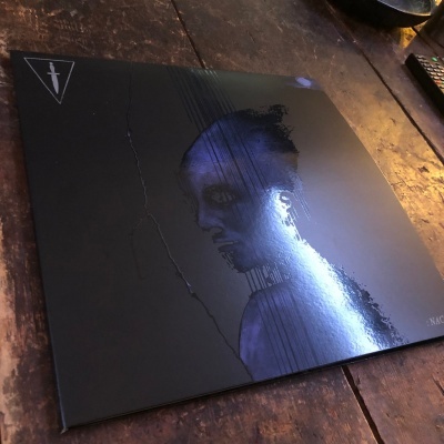 Capa de disco de vinil preta com rosto em azul e símbolo triangular branco