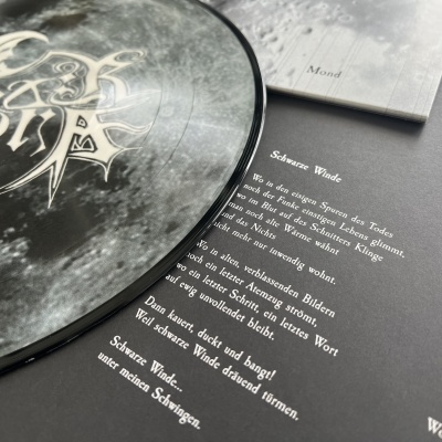 Disco de vinil preto com capa e texto alemão ao lado em fundo preto