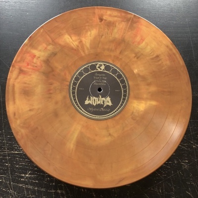 Disco de vinil laranja marmoreado com rótulo preto e branco ao centro