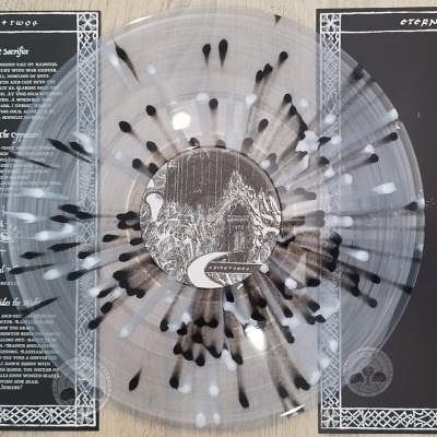 Vinil transparente com manchas pretas e brancas numa capa dupla preta e branca com texto e imagens