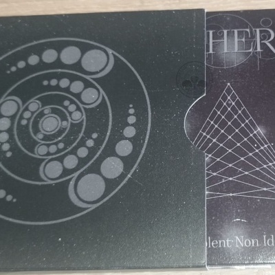 Caixa e capa de CD preta com desenhos geométricos e texto HERE