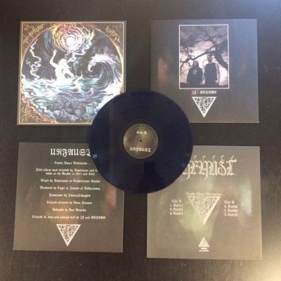 Vinil preto com capas ilustradas e texto em inglês sobre superfície cinzenta