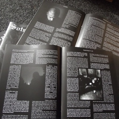 Fanzine ou revista aberta com texto em inglês sobre fundo preto e várias páginas em carpete cinzenta.
