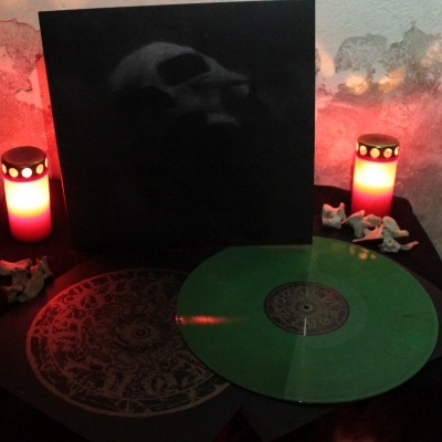 Disco vinil verde translúcido com capa preta e dois candeeiros vermelhos acesos