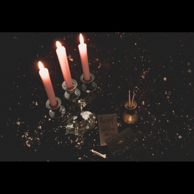 Conjunto de três velas acesas em castiçal de metal prateado com acessórios ao redor sobre mesa preta