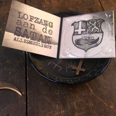 CD aberto com capa e CD branco com brasão, sobre placa preta e mesa de madeira escura.