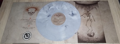 Disco de vinil translúcido cinzento com capa aberta ilustrada com caveiras e esqueletos